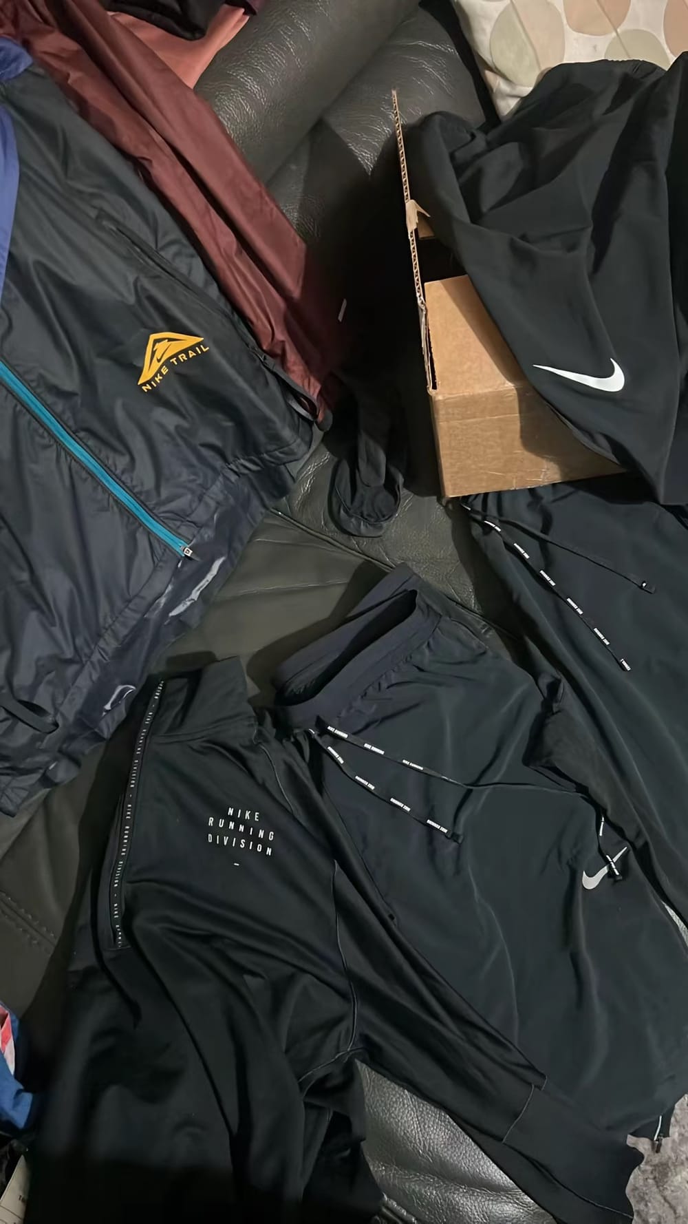 Des pièces Nike Running Division et Nike Trail posées sur un canapé